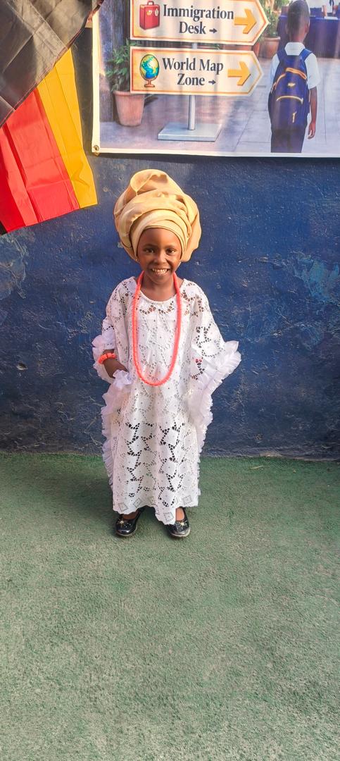 A pupil in white lace and gele for Global Tour Passport Day
