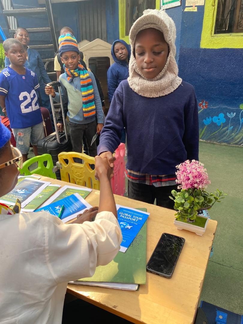 A pupil shaking hands with a staff member at the check-in desk