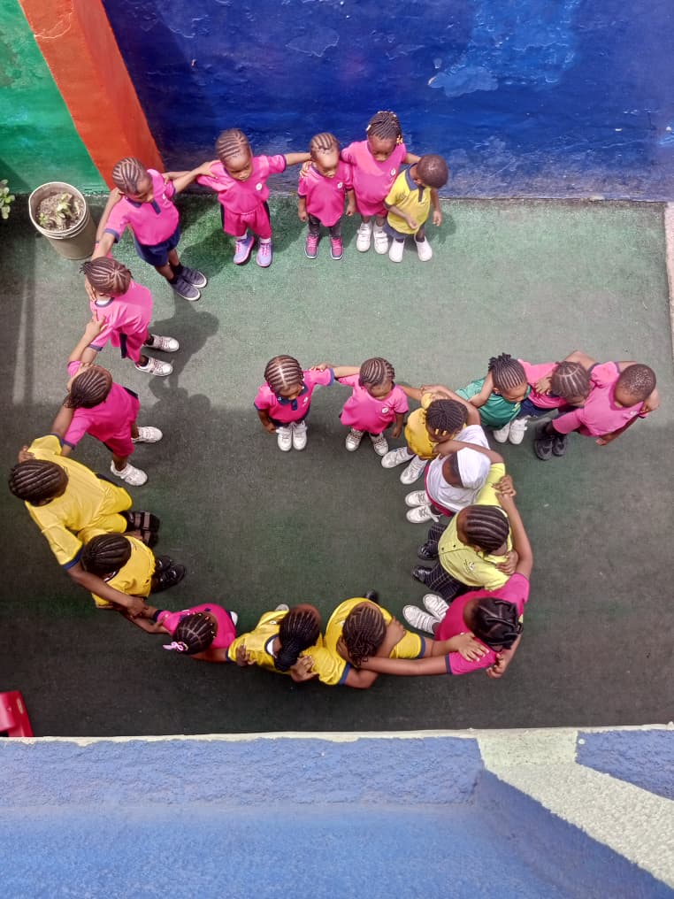 Pupils in house colours forming a circle together on the playground