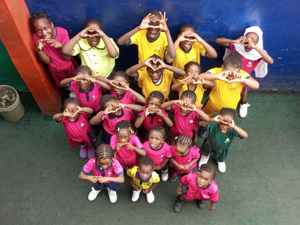 Pupils in house colours making heart shapes with their hands